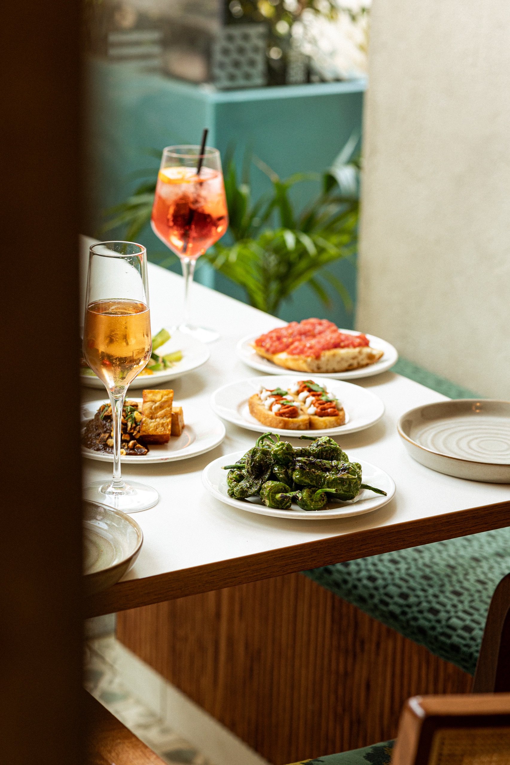 Spritz, cava and tapas plates on a window table, glimpsed through the doorway