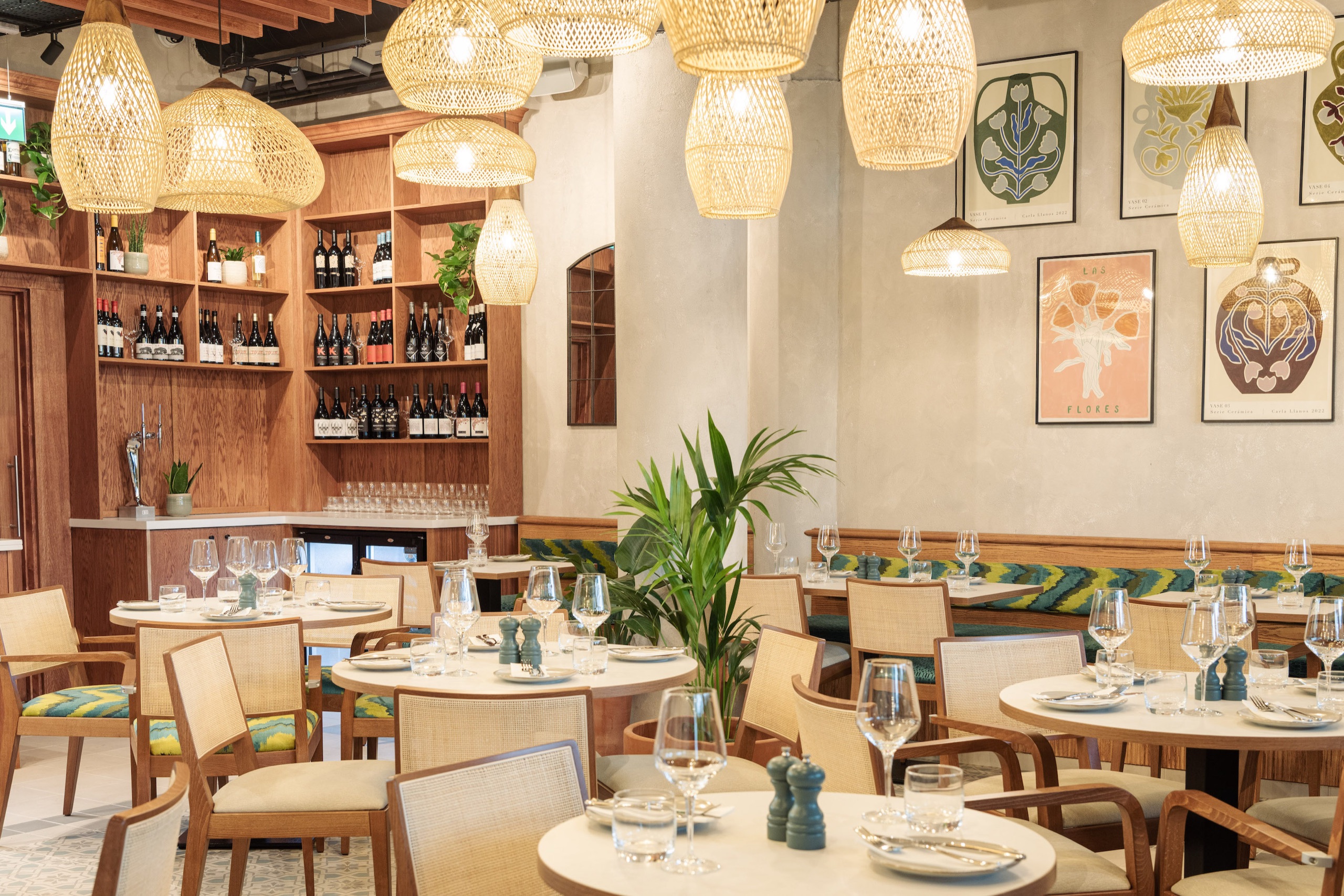 La Gamba's bright dining room with rattan lamps, a wine wall, art and round tables laid for lunch (photo: Rebecca Dickson)